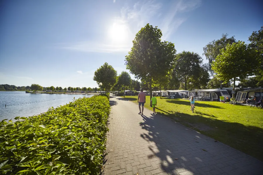 mensen wandelen naast het water over de camping